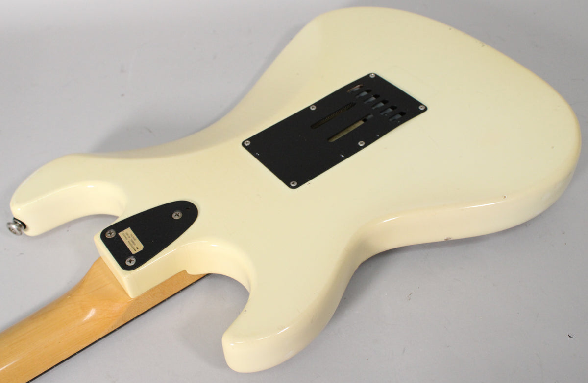 The back of an Olympic White guitar, showing the tremolo cavity cover, neck plate, and some minor finish wear.