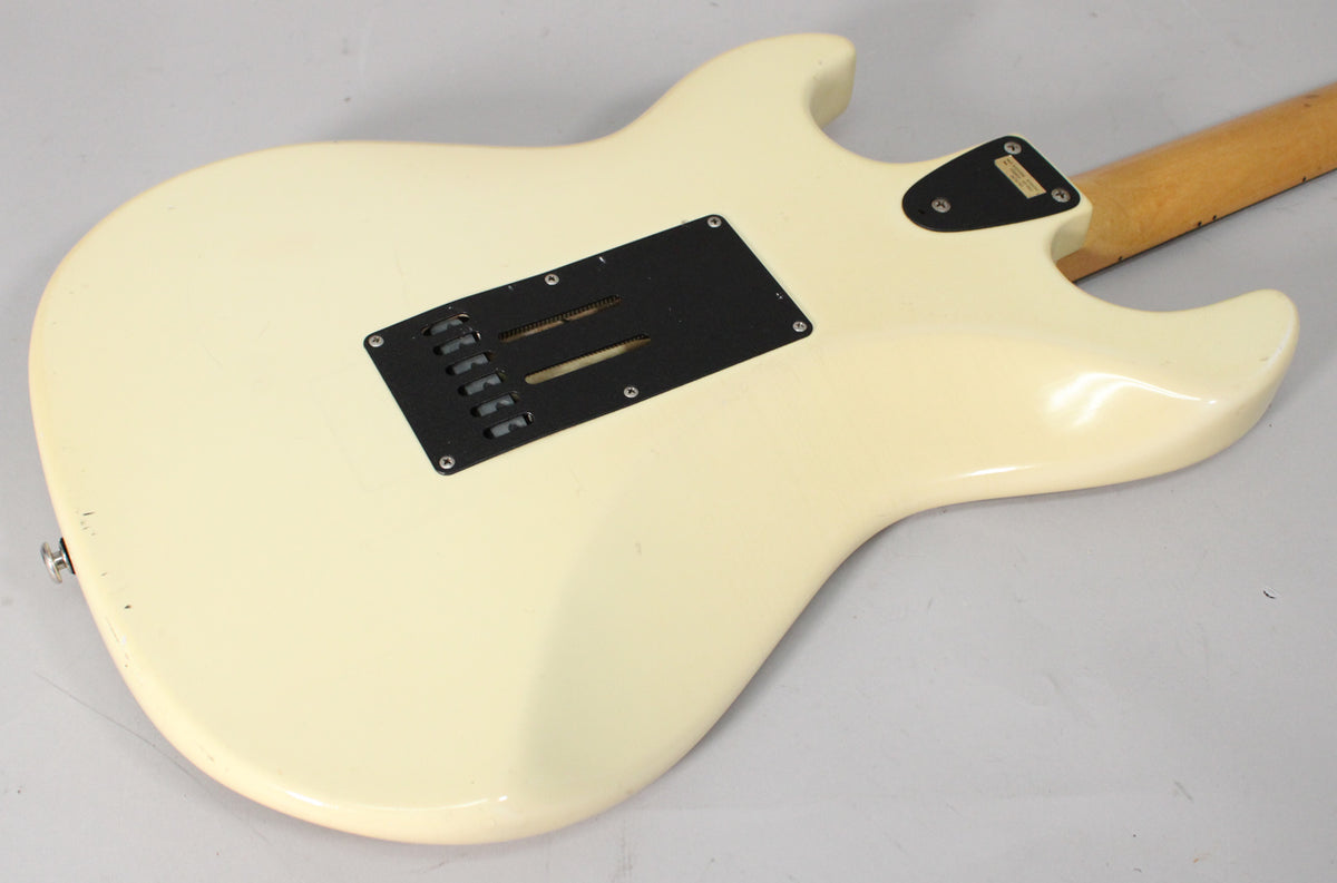 The back of an Olympic White guitar, showing the tremolo spring cover, neck plate, and some finish wear on the lower bout.