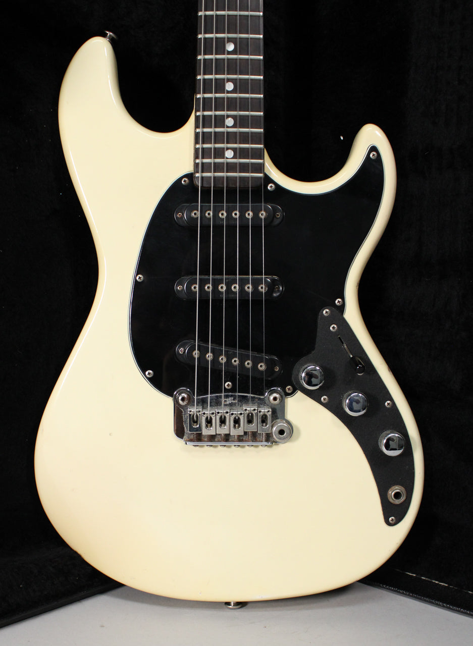 The Olympic White guitar body, with a black pickguard and three single-coil pickups, shows some minor wear and tarnished chrome hardware.