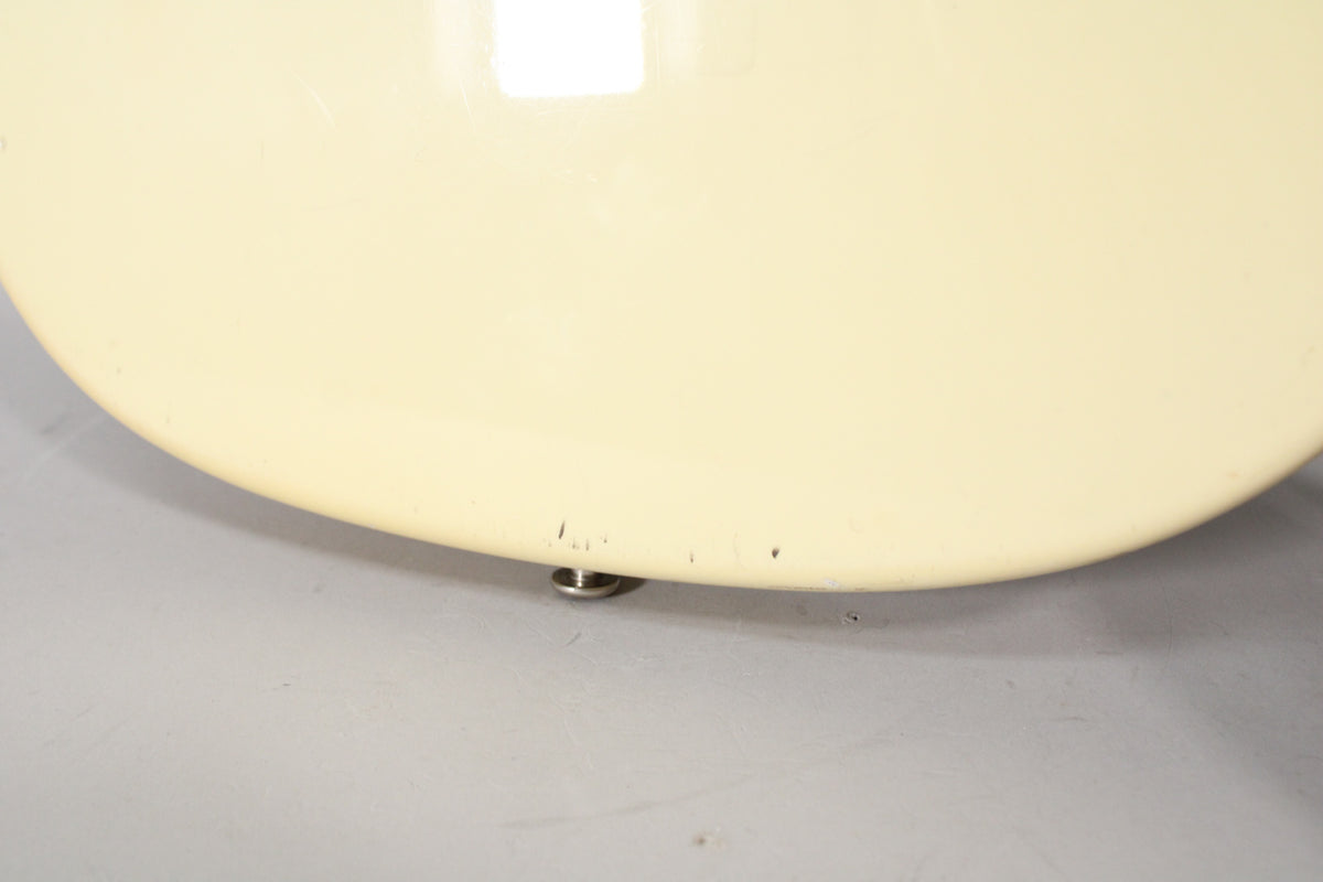 Close-up of the guitar's lower bout in Olympic White, showing several small chips and scuffs along the bottom edge and a strap button.