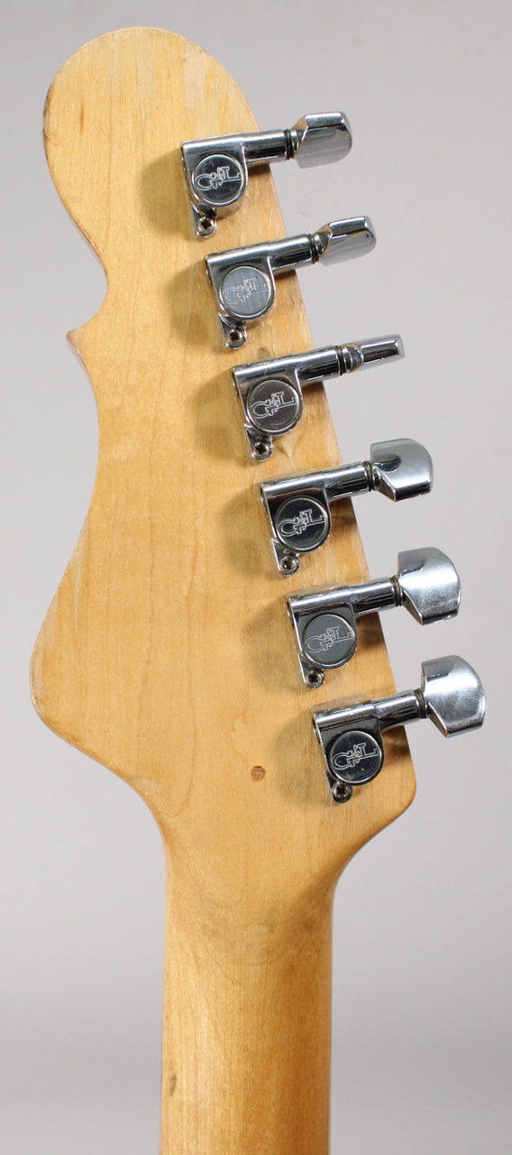 The back of a light wood headstock and neck, showing six chrome tuners with G&L logos and light wear.