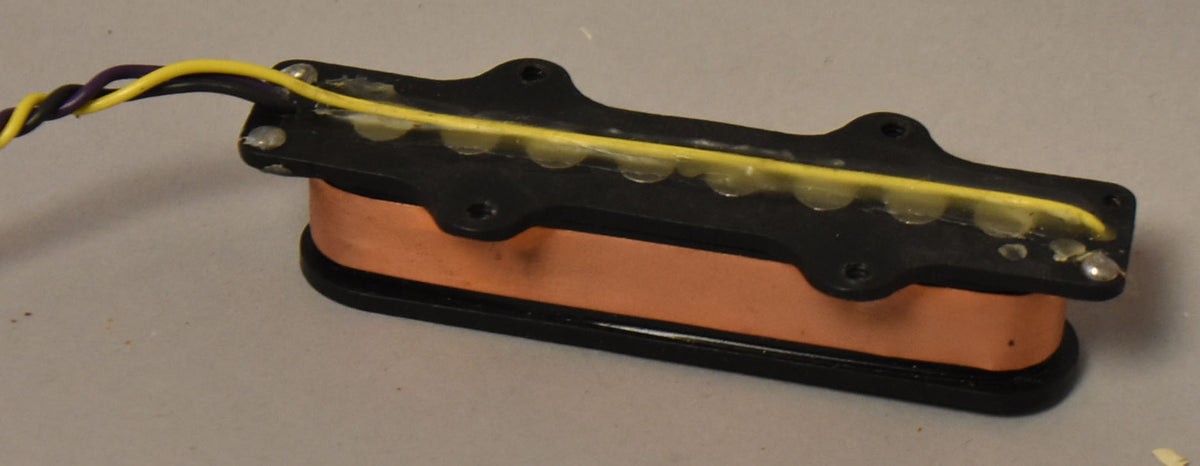 Black pickup with a copper coil, viewed from above at an angle, showing yellow and purple wires emerging from the left.