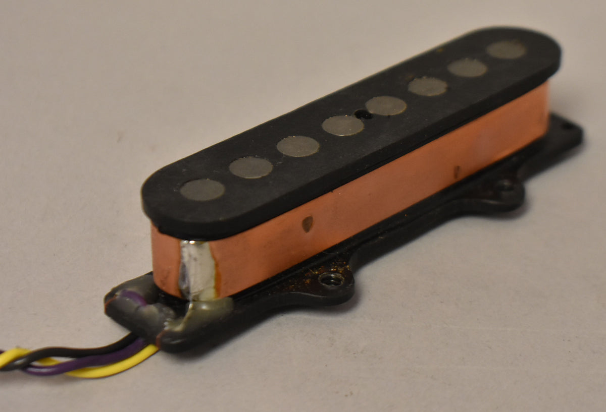 Angled view of a black pickup with eight round pole pieces, copper coil wiring, and exposed yellow, purple, and black wires.