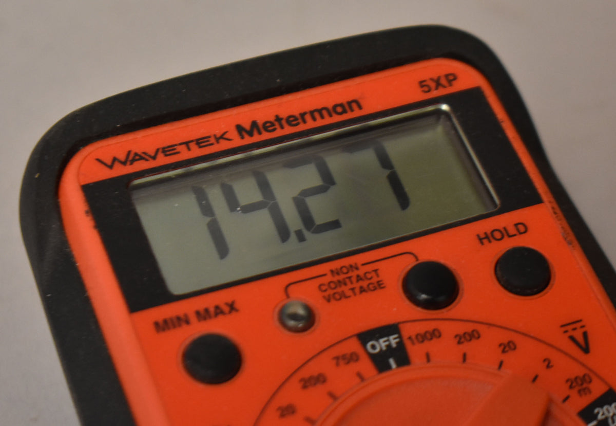 Close-up of an orange Wavetek Meterman 5XP multimeter displaying "14.27" on its screen.