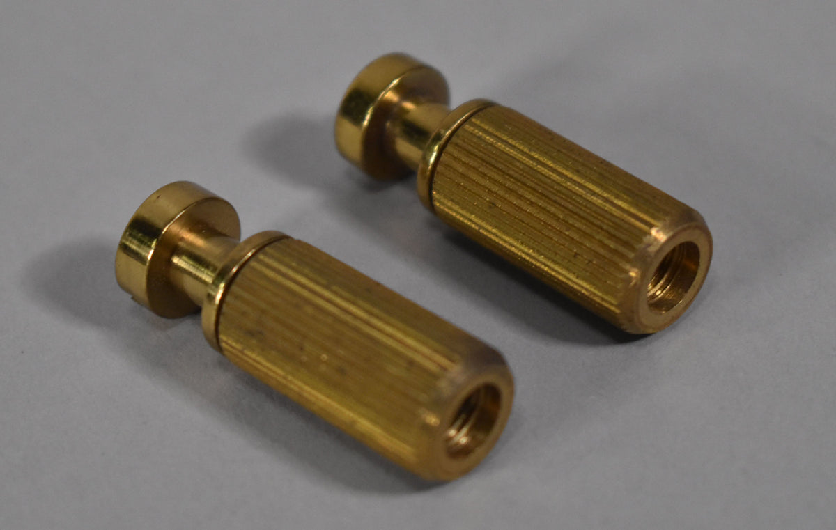 Two brass stoptail studs and bushings, viewed from above, showing the knurled sides and threaded interiors.