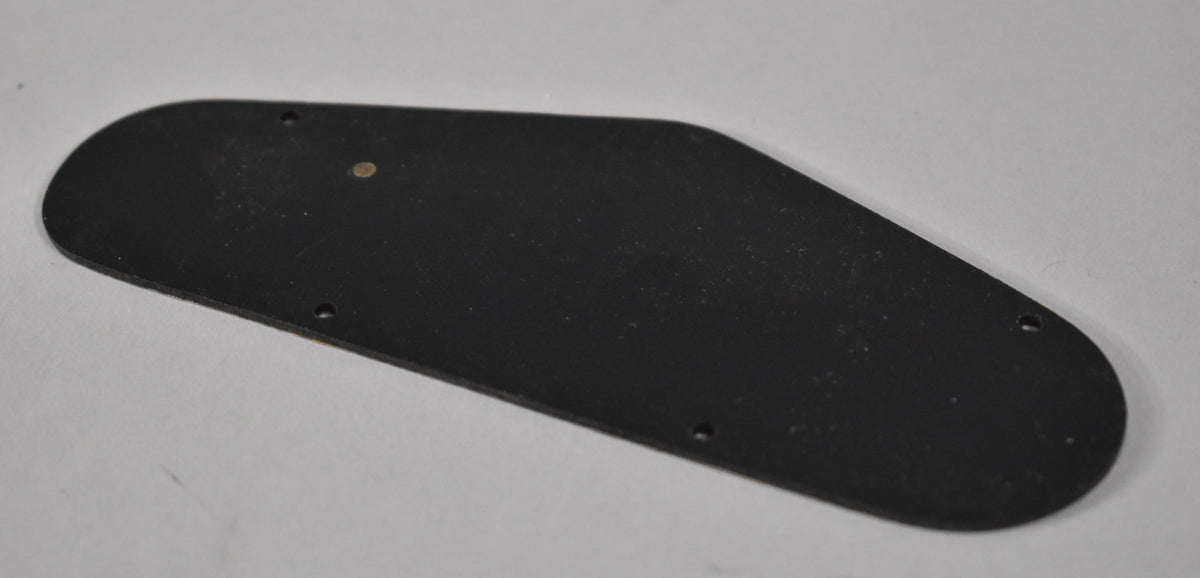 A black plastic control cavity back plate, viewed from above, showing five screw holes and a small brass-colored dot.