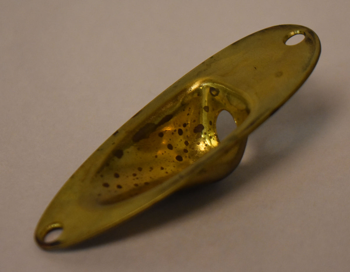 A gold brass input jack cup, viewed from above, showing dark patina spots and two mounting holes on either end.
