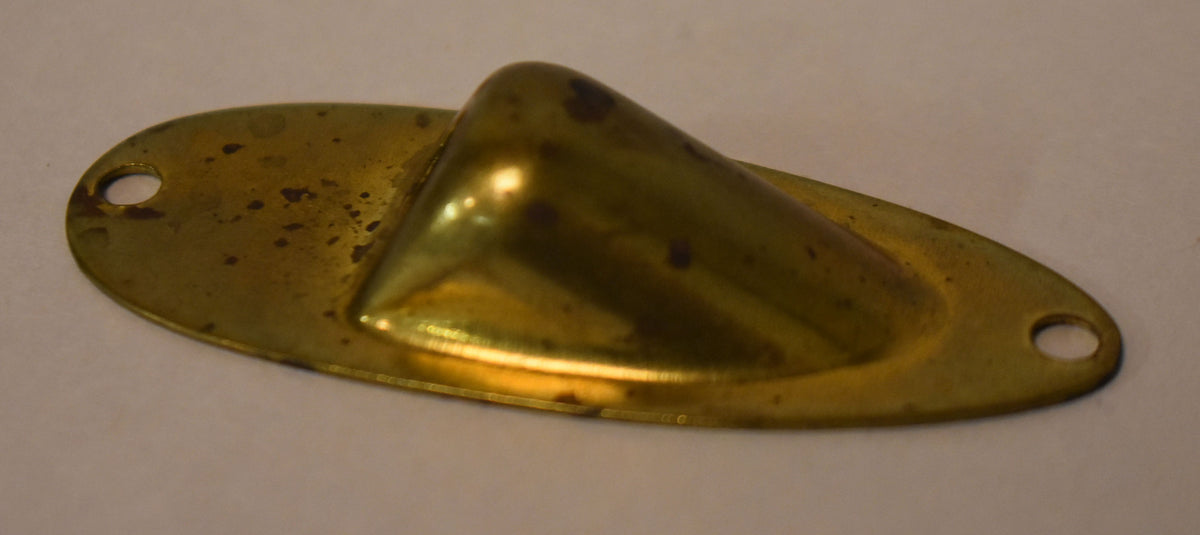 A gold brass input jack cup, viewed from above, shows a conical protrusion and two screw holes, with visible dark patina.