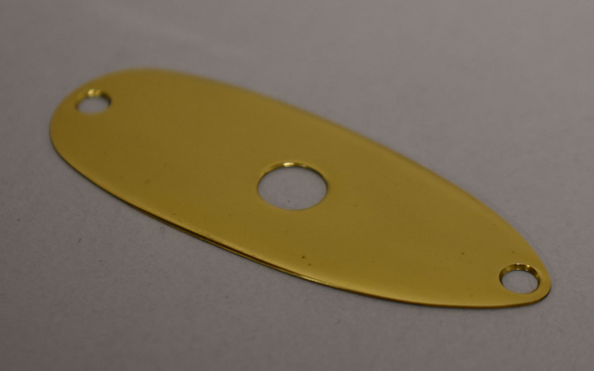 A shiny, teardrop-shaped brass input jack plate with a central jack hole and two smaller screw holes, one at each end.