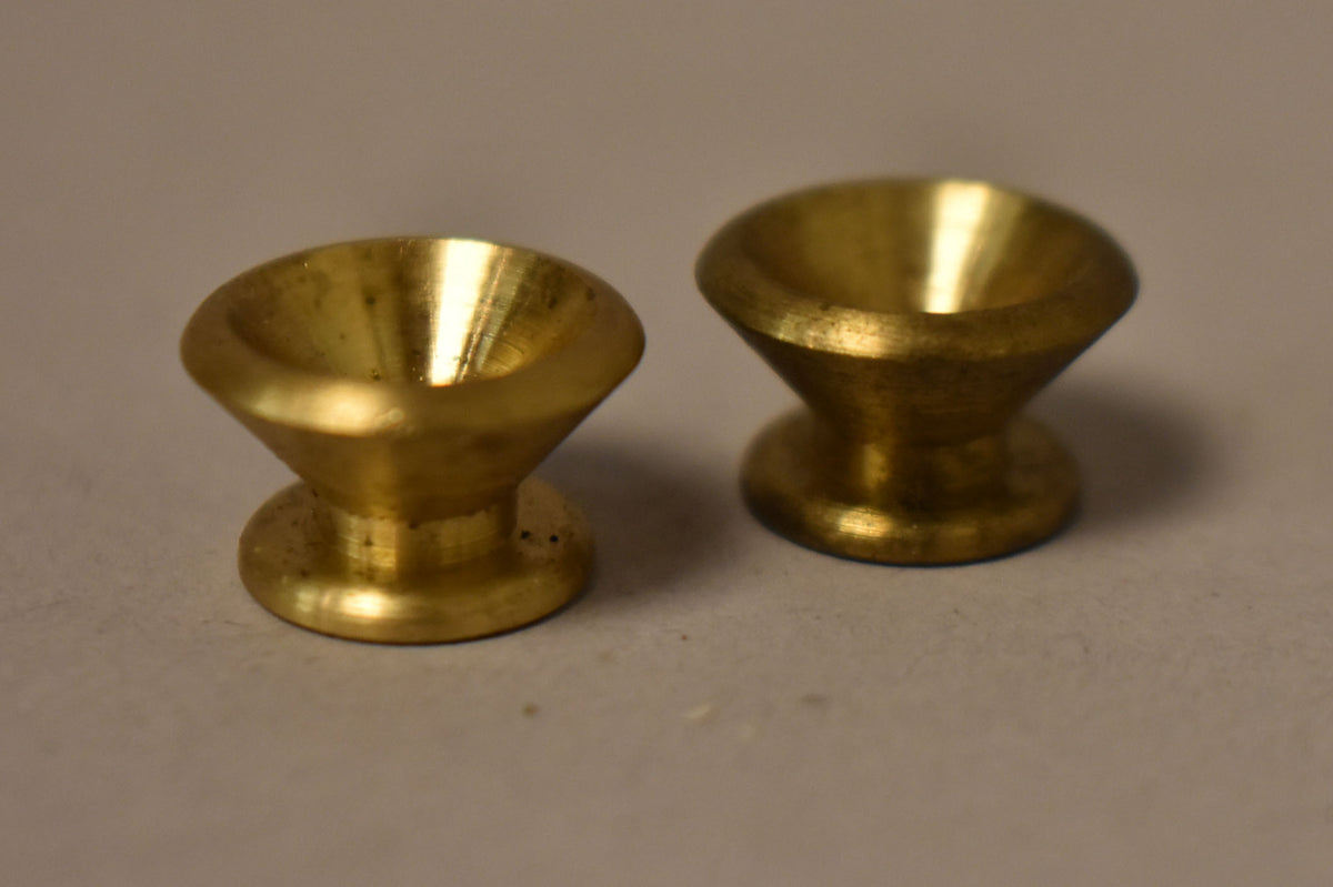 Two gold-finished strap buttons, each with a flared top and a narrow waist, are angled slightly from above.