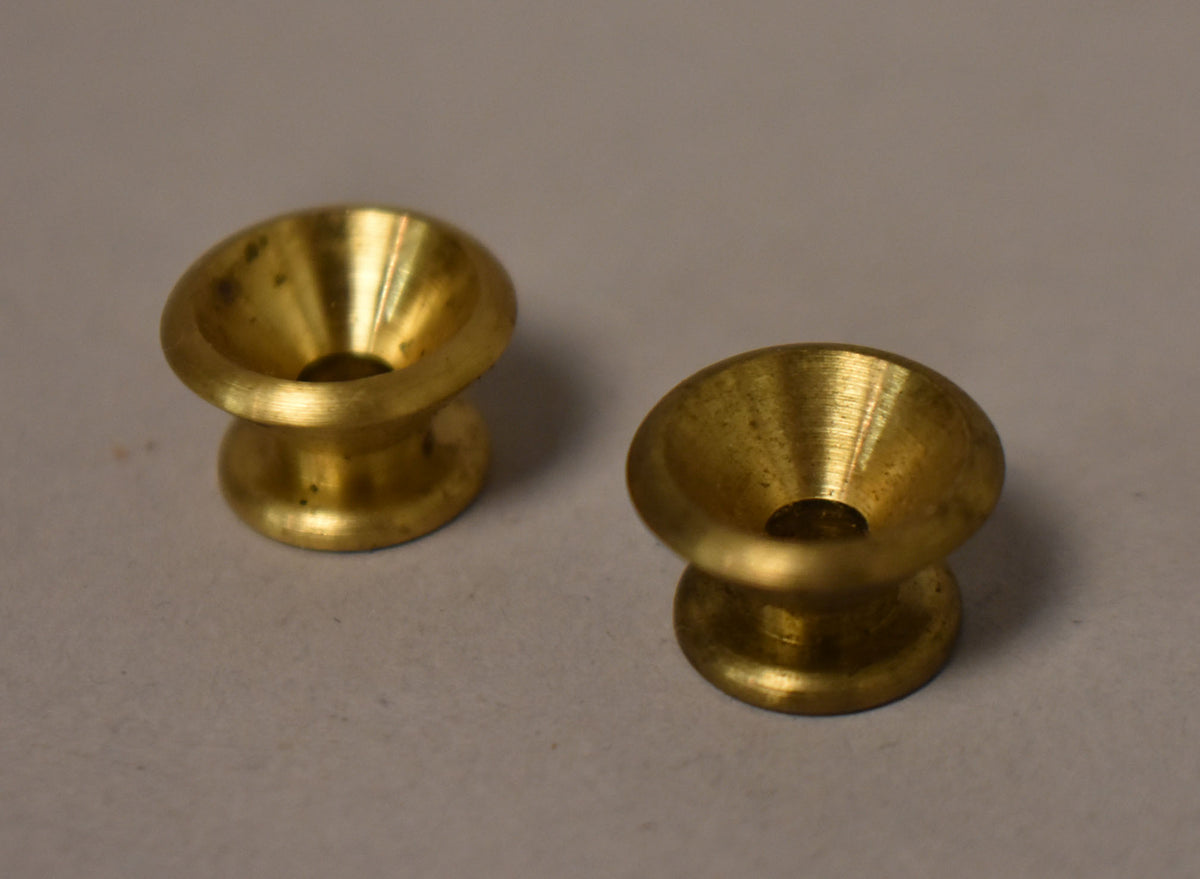 Two gold strap buttons, viewed from above, show a conical top with a small central hole and a cylindrical base.