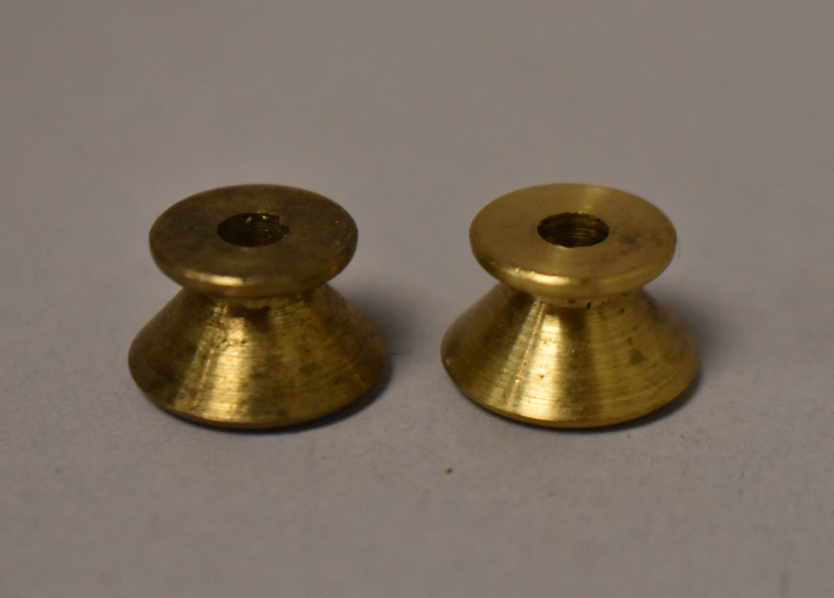 A pair of gold strap buttons with a conical base and a flat top, showing fine concentric machining marks and some patina.