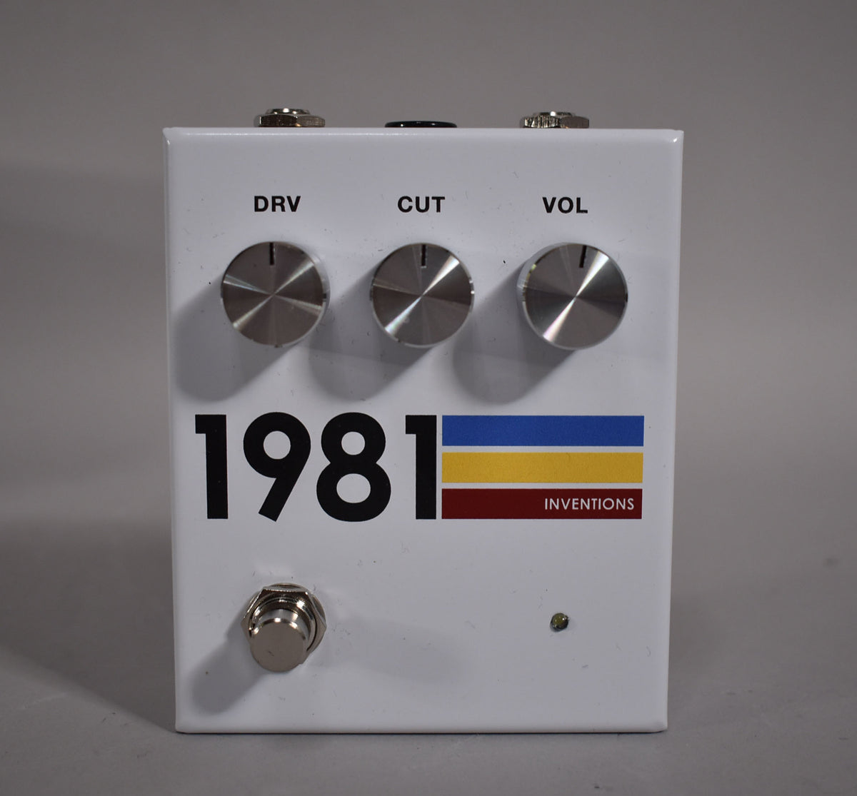 White pedal with three silver control knobs labeled DRV, CUT, and VOL, a footswitch, and a small green indicator light.