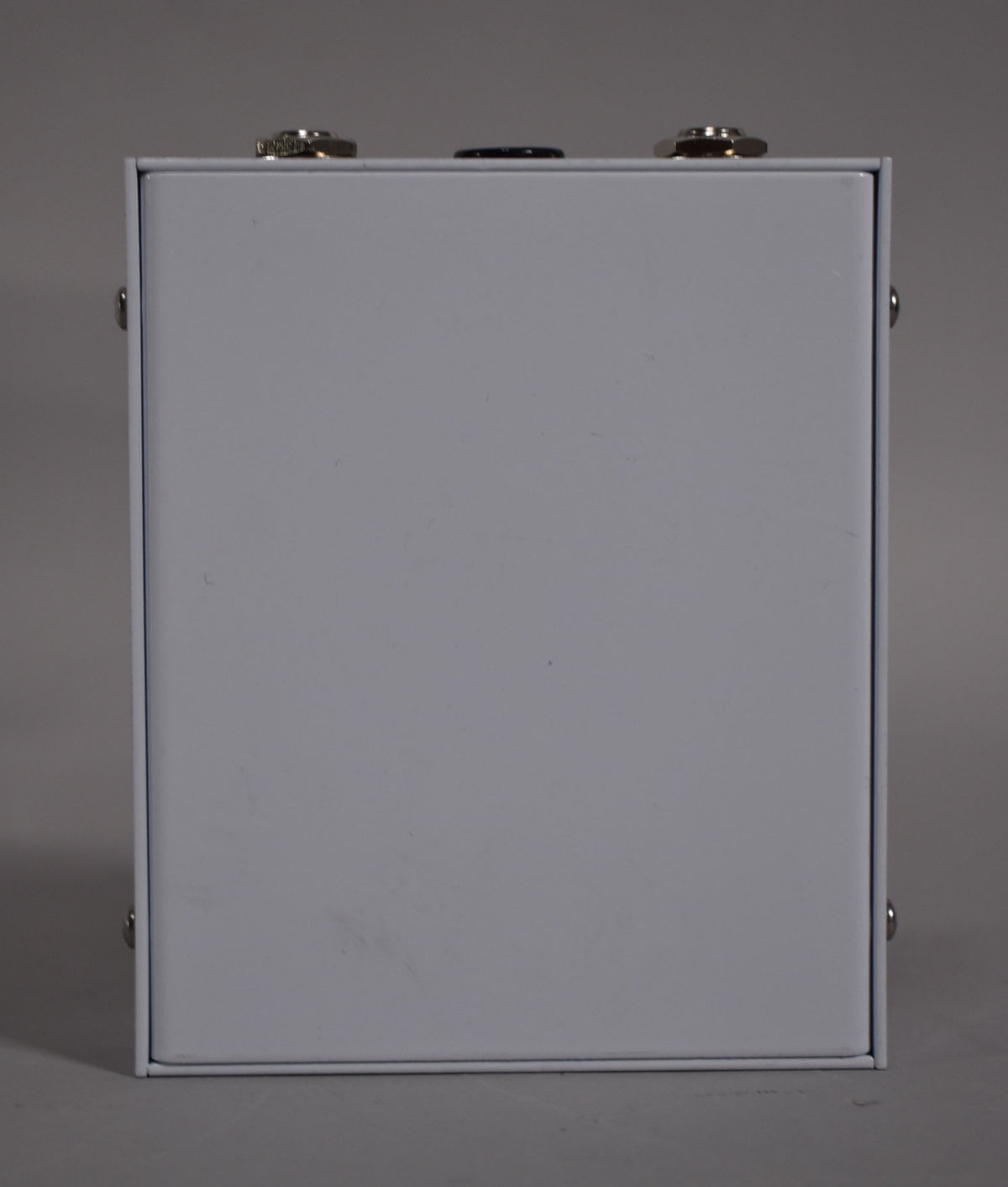 The white pedal is viewed from the side, revealing a few minor scuffs and two chrome jacks and a black knob on the top edge.