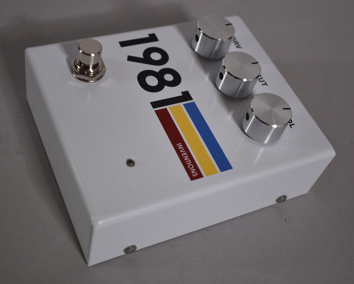 White pedal with a large black "1981" and a red, yellow, and blue stripe, featuring a chrome footswitch and three chrome knobs.