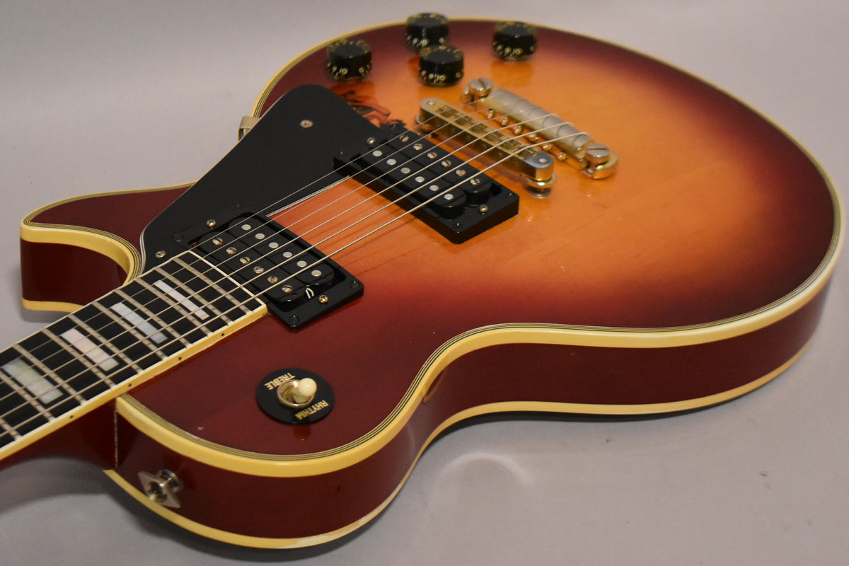 Close-up of the cherry sunburst body, showing the bridge, tailpiece, black pickups, pickguard, and volume/tone knobs.