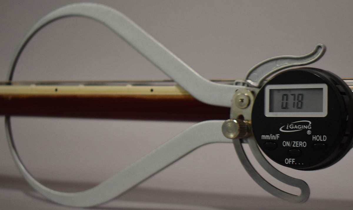 A digital caliper measures the guitar's dark cherry sunburst neck, showing a reading of 0.78.