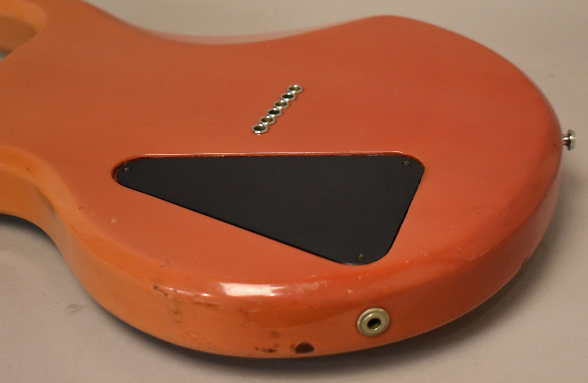 The faded pink guitar's back shows a black triangular control cavity cover, six string-through-body ferrules, and a worn input jack.