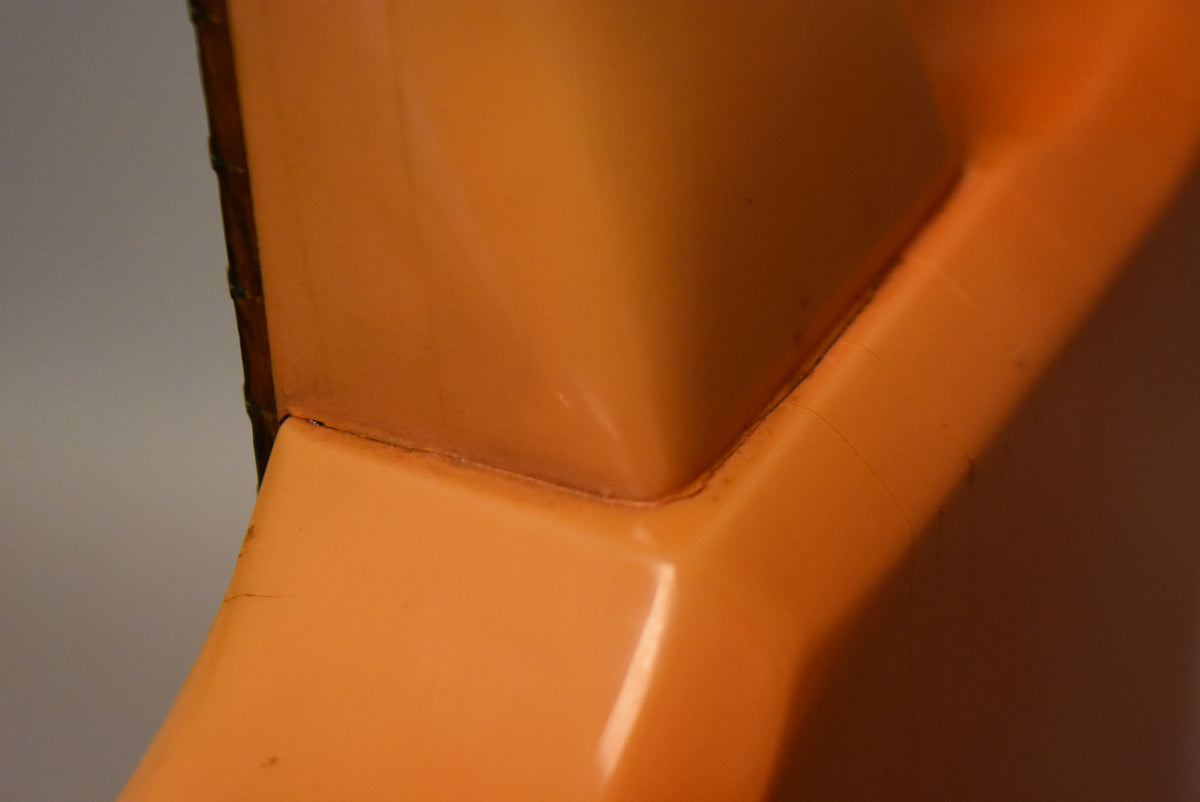 Close-up of the guitar's faded pink body, showing finish checking and wear along the edges and seams.