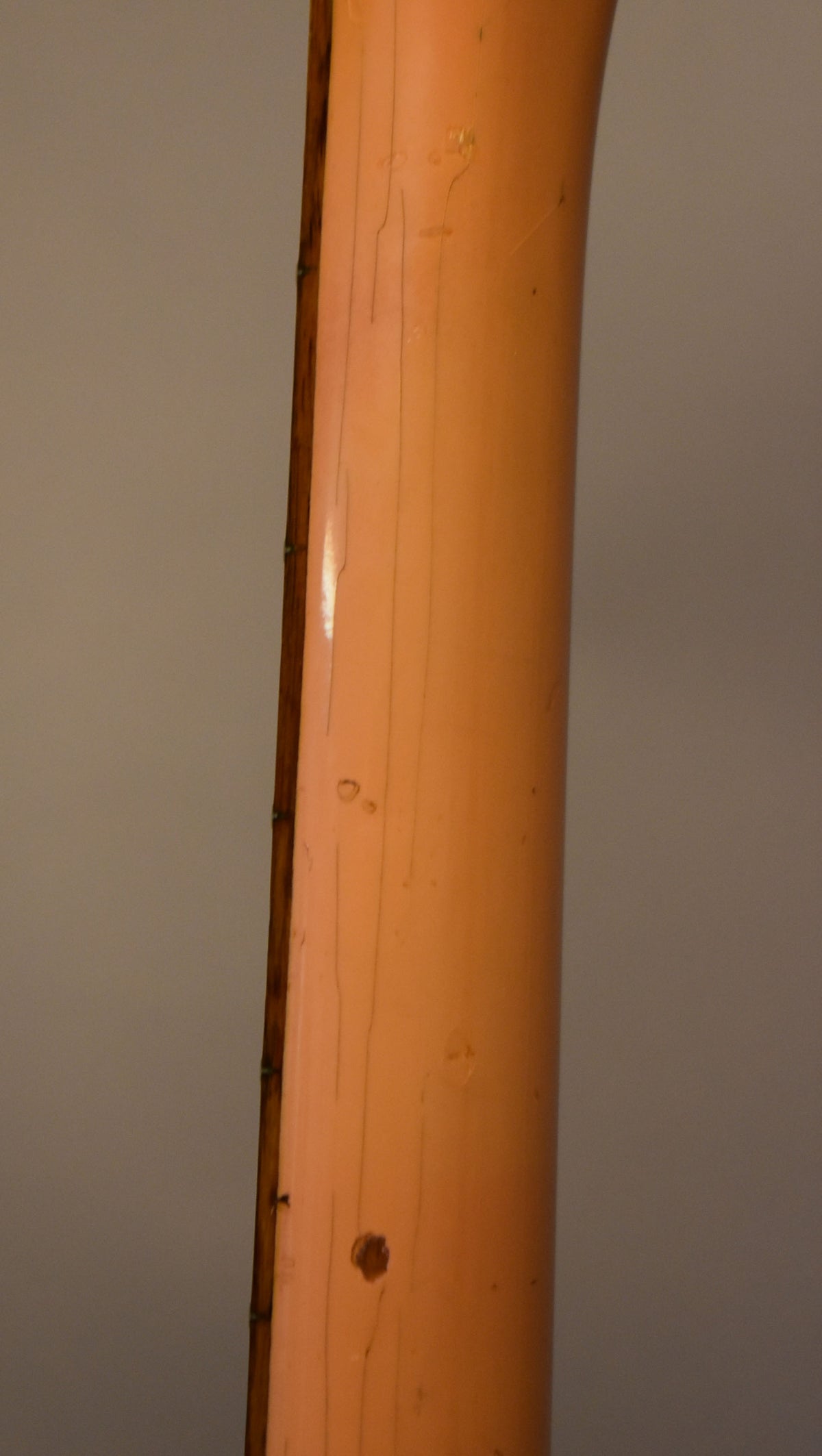 Close-up of the guitar neck's faded pink finish, showing extensive lacquer checking, dings, and wear along the fretboard edge.