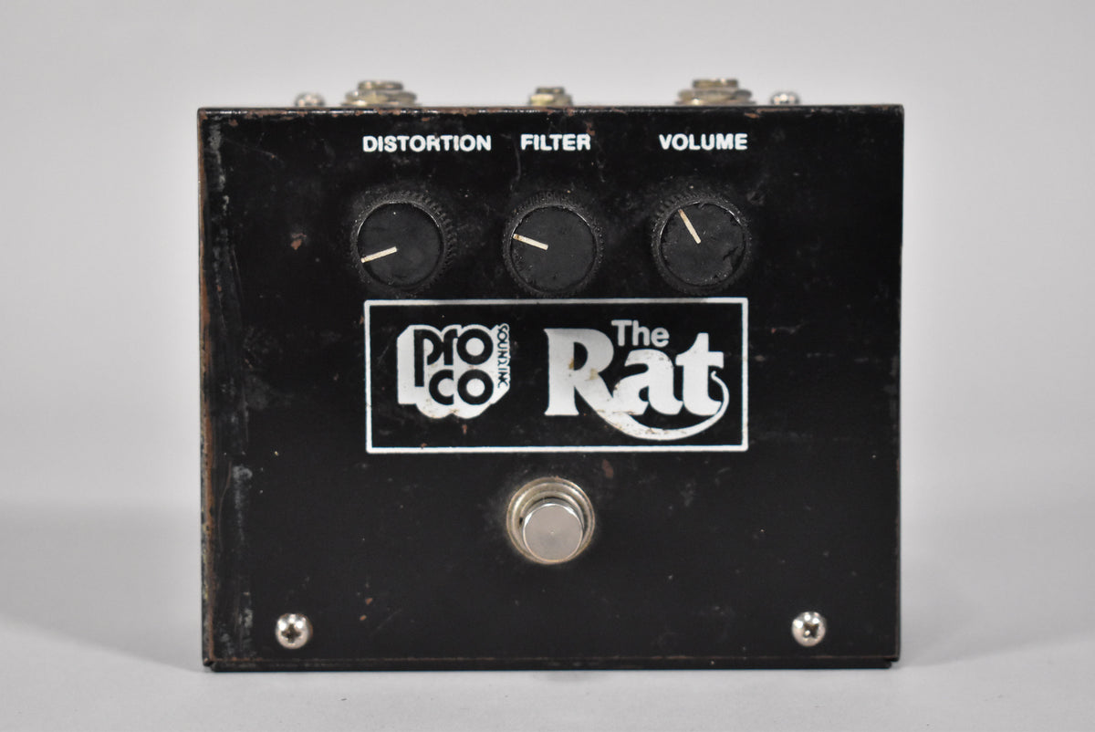 Front view of a worn black distortion pedal with three top-mounted black control knobs labeled "DISTORTION", "FILTER", and "VOLUME", and a single footswitch.