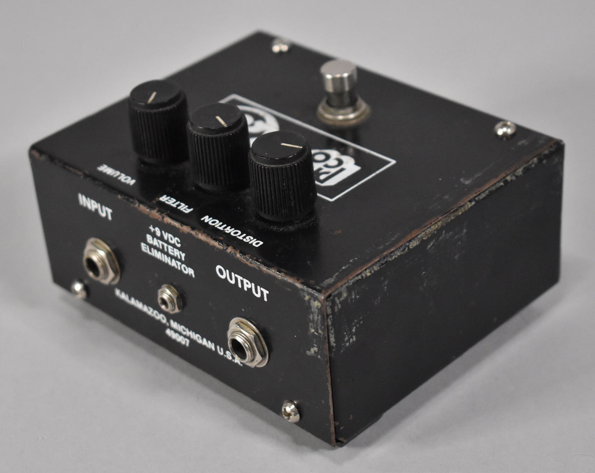 Black pedal from above, showing three ridged control knobs, a footswitch, and input/output jacks with visible paint wear on edges.