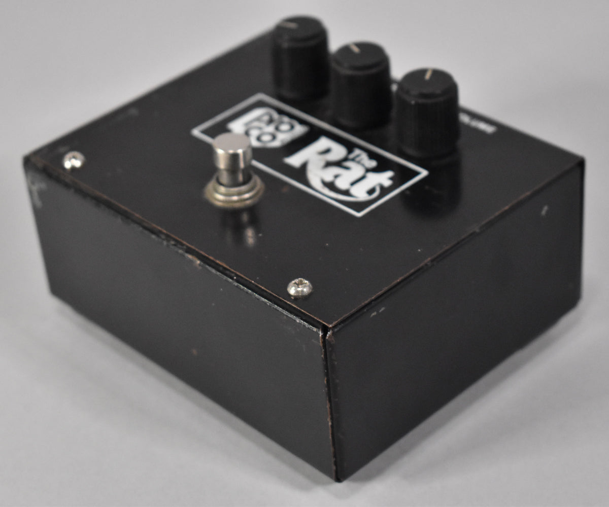 Black rectangular pedal with three black knobs and a silver footswitch, showing wear along the edges and corners.