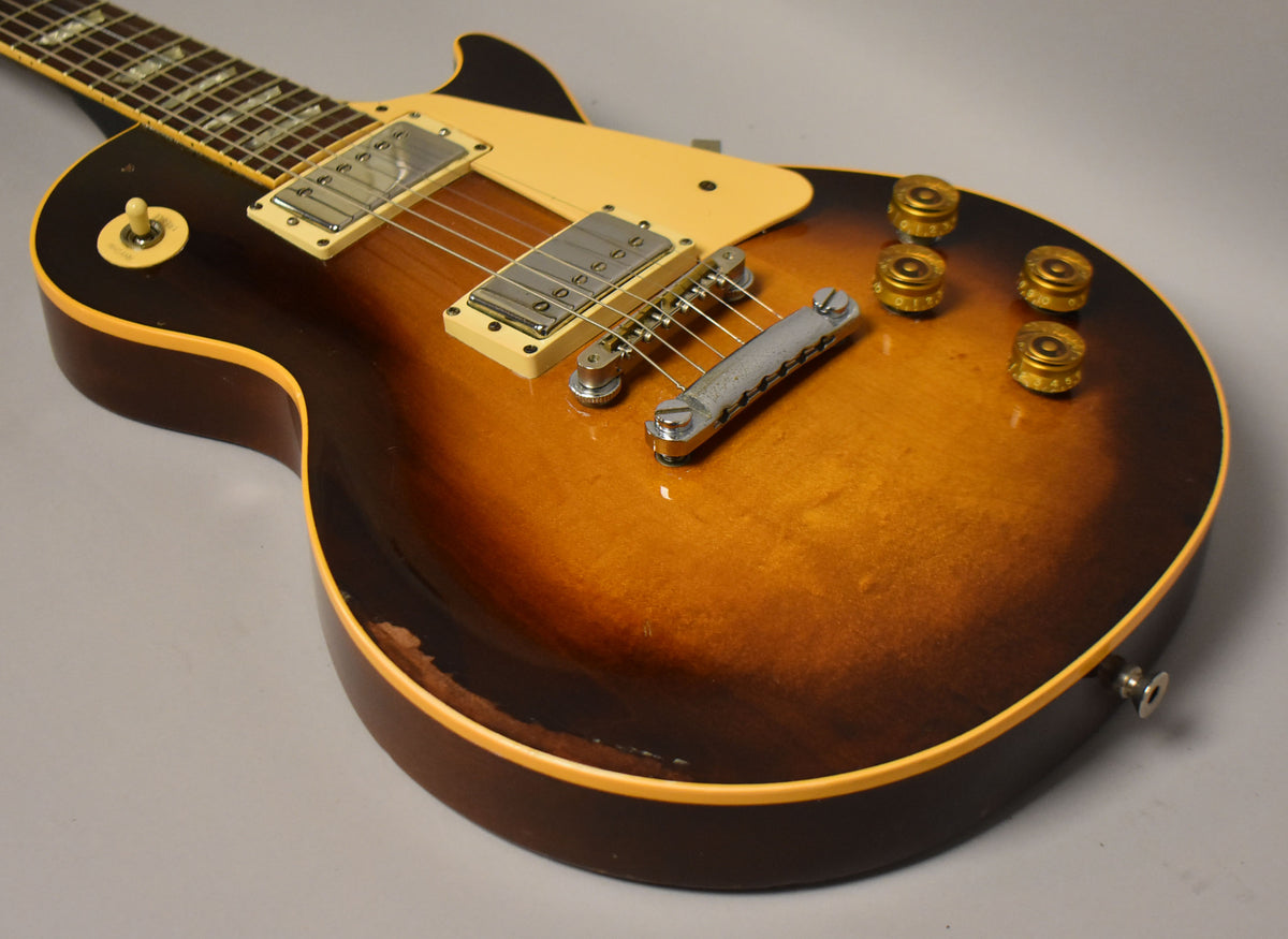 Upper body of a tobacco burst guitar, showing two humbuckers, four gold speed knobs, and significant finish wear on the lower bout.