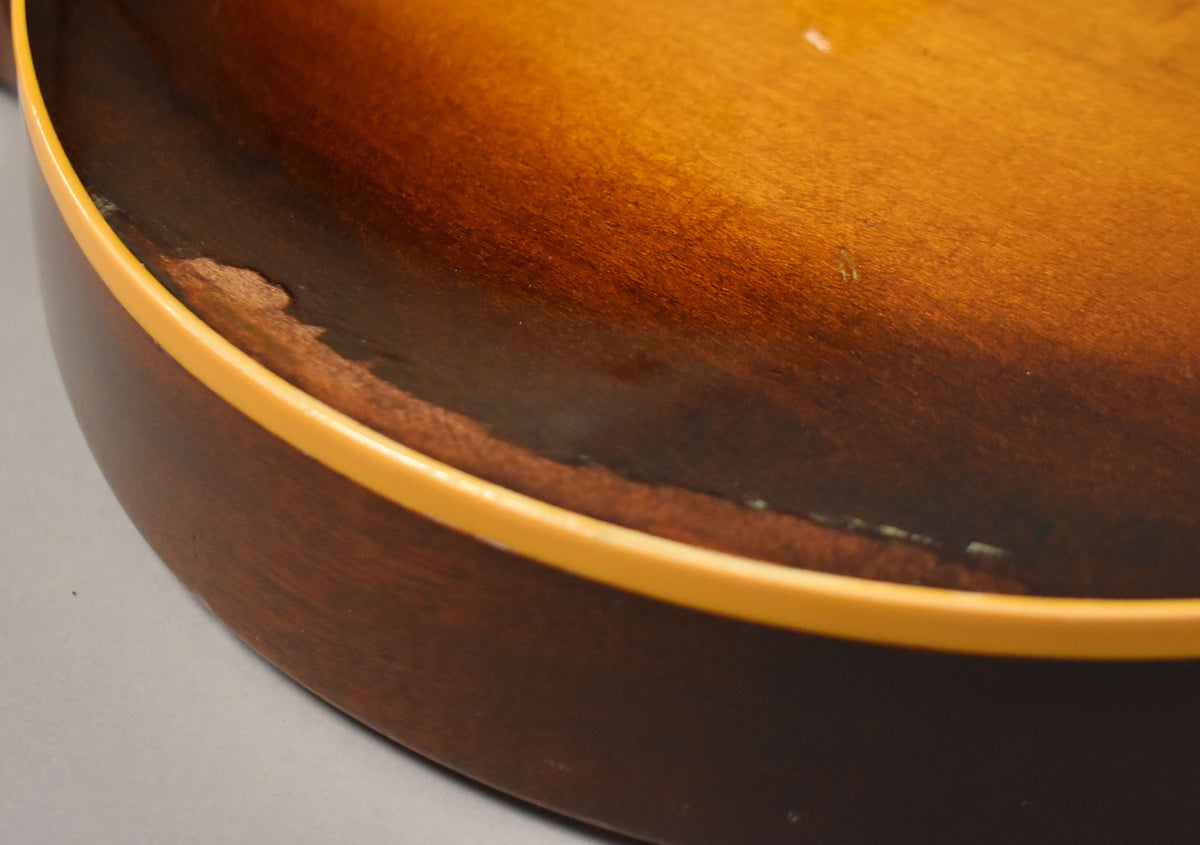 Close-up of the lower bout, showing significant finish wear and chipping along the cream binding and dark brown edge of the tobacco burst.