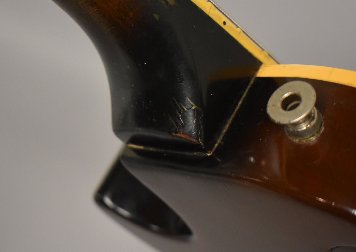 Close-up of the guitar's neck heel and upper body, showing finish checking and wear on the dark brown and black tobacco burst.