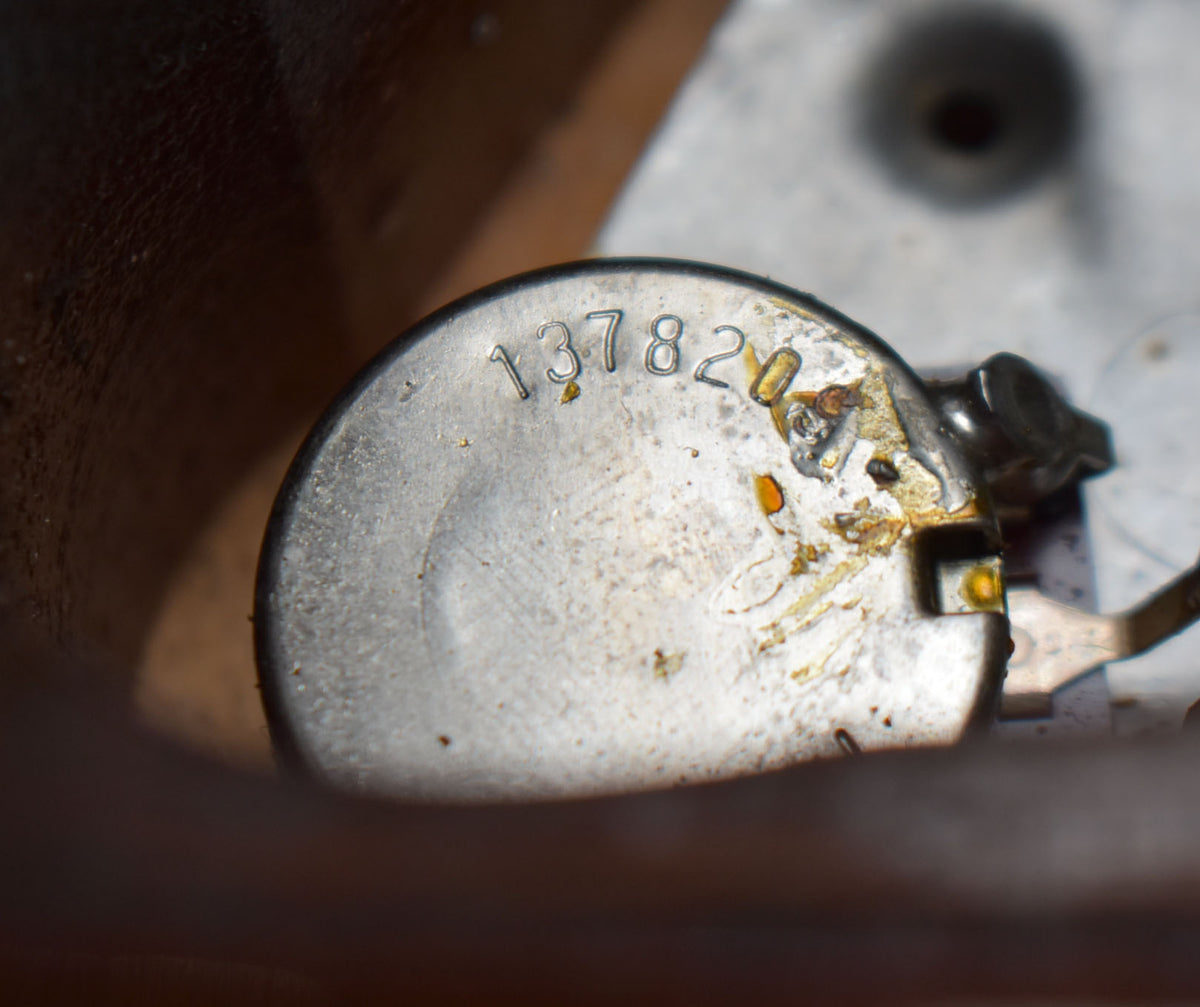 Close-up of a tarnished metal potentiometer with "137820" stamped on it, showing solder residue and wear.