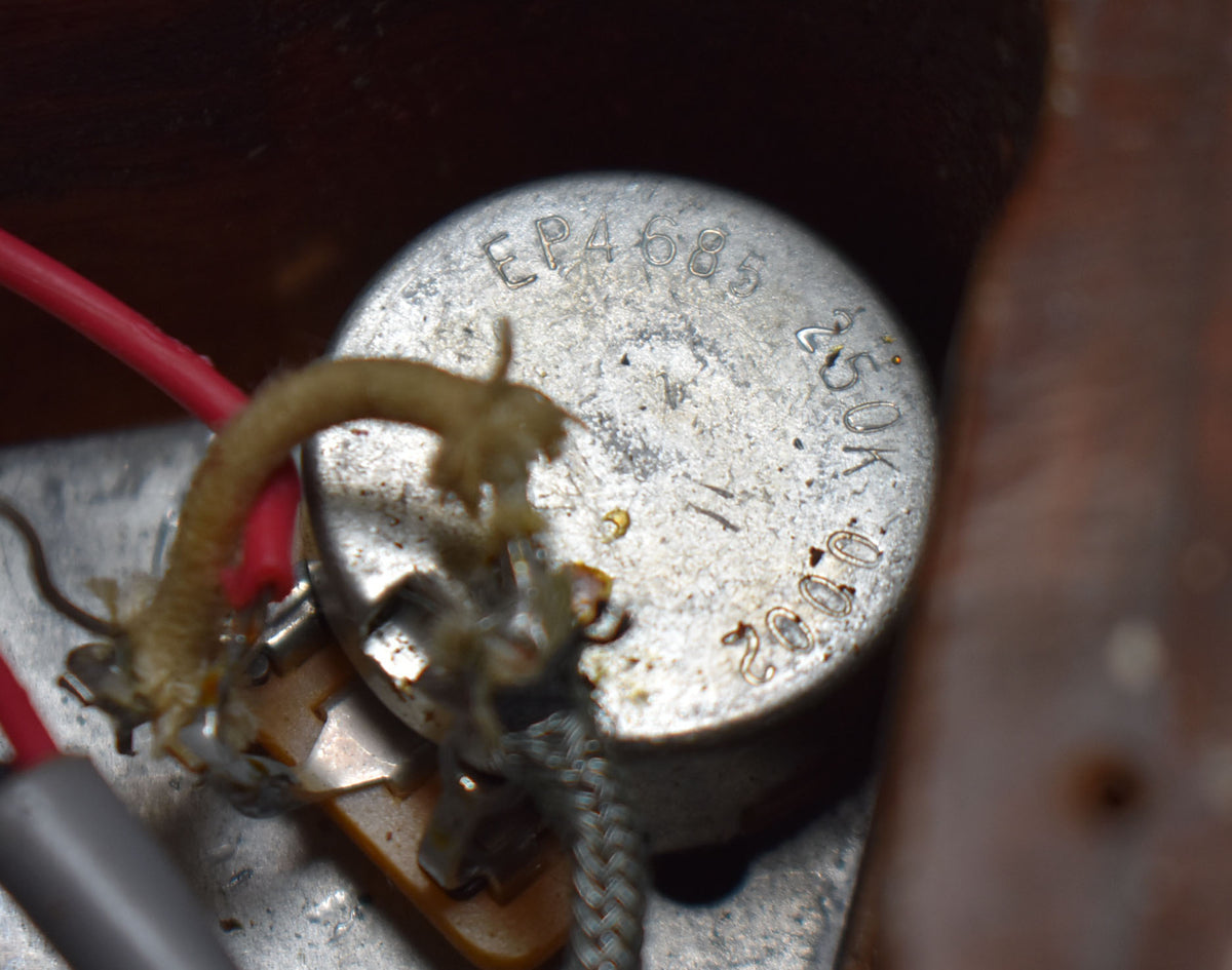 Close-up of a tarnished silver potentiometer with "EP4685 250K 2002" stamped on top, surrounded by red and braided wires.