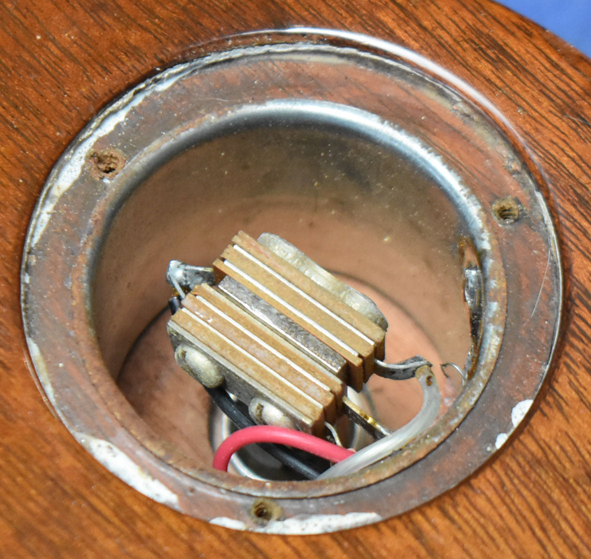 Close-up of the output jack cavity, showing the metal jack, wiring, and a worn, chipped tobacco burst finish around the edge.