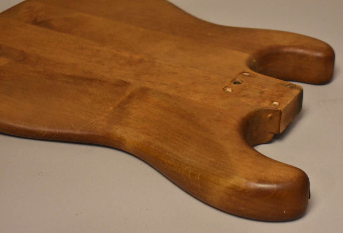 The stripped natural guitar body is angled from the upper left, showing the neck pocket and lower horn with visible wear.