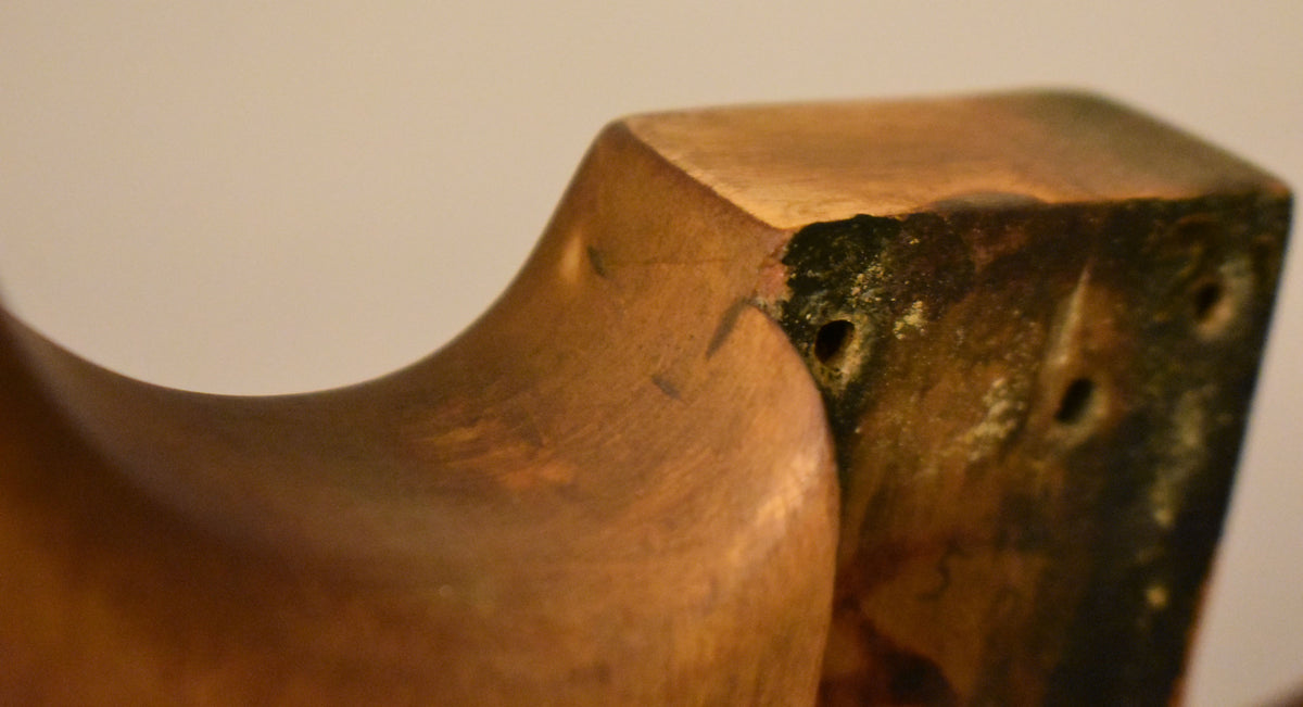 Close-up of the neck pocket, showing dark green residue, chipped wood, and three screw holes on the body's end.