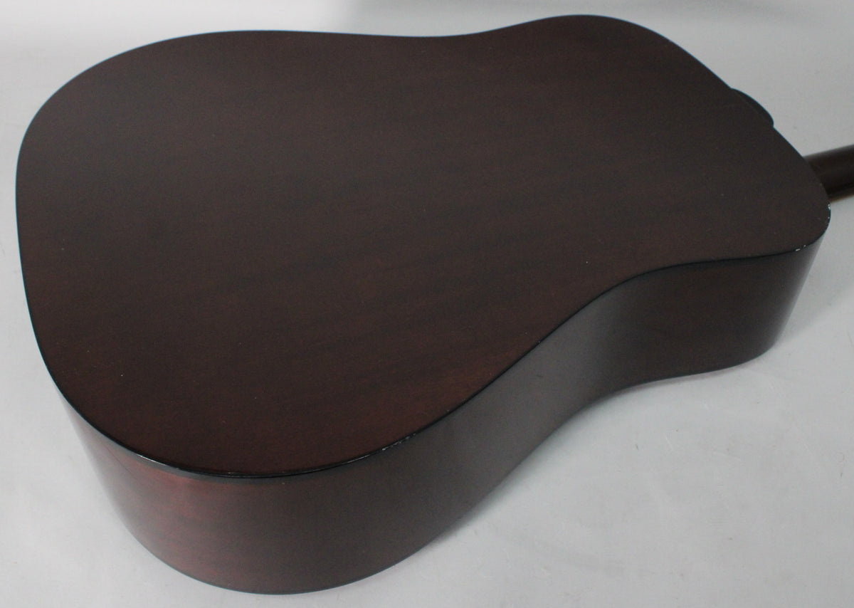The guitar's dark brown back and sides are shown from an overhead angle, with some light wear visible on the lower bout.