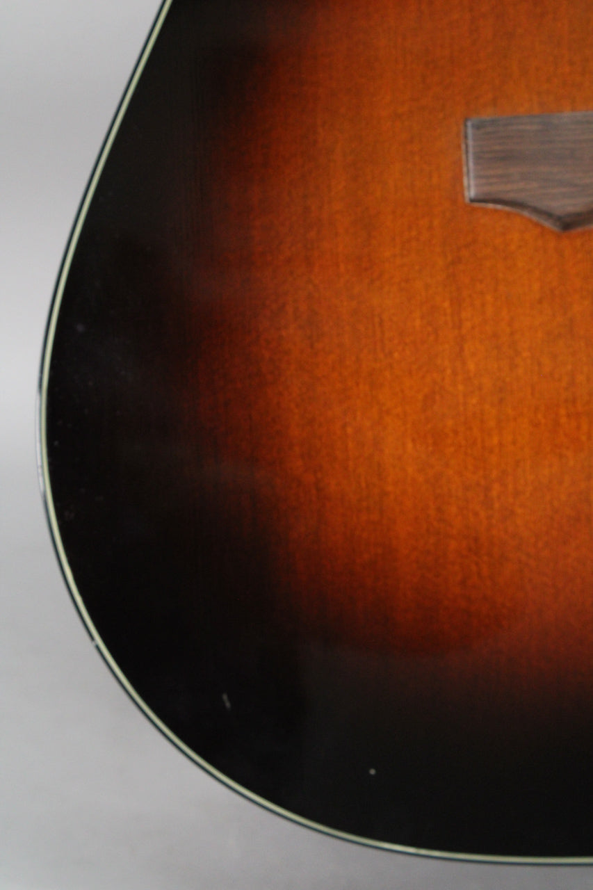 Close-up of the guitar's lower bout, showing the dark sunburst finish with some minor dings and a small part of the bridge.