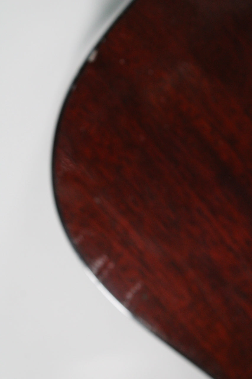 Close-up of the guitar's dark red sunburst body, showing light wear and small chips along the binding on the upper bout.