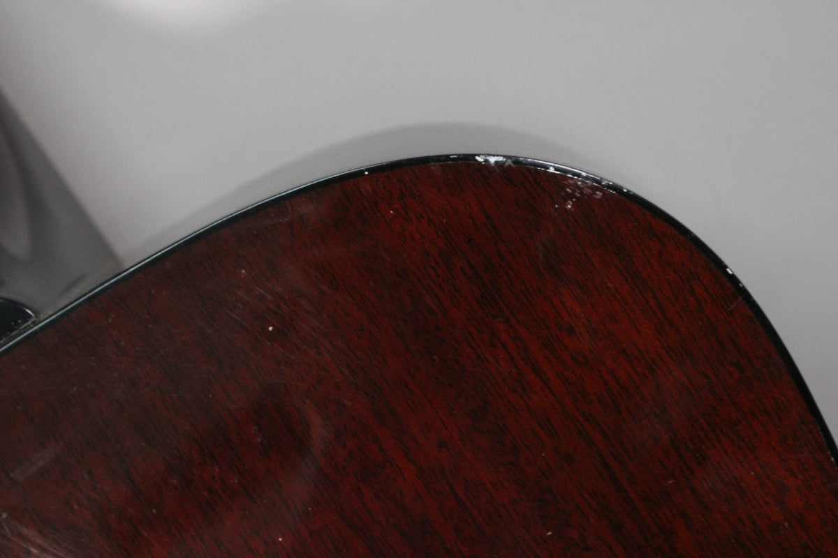 Close-up of the guitar's dark sunburst body, showing a chipped finish along the upper bout's edge and light surface wear.