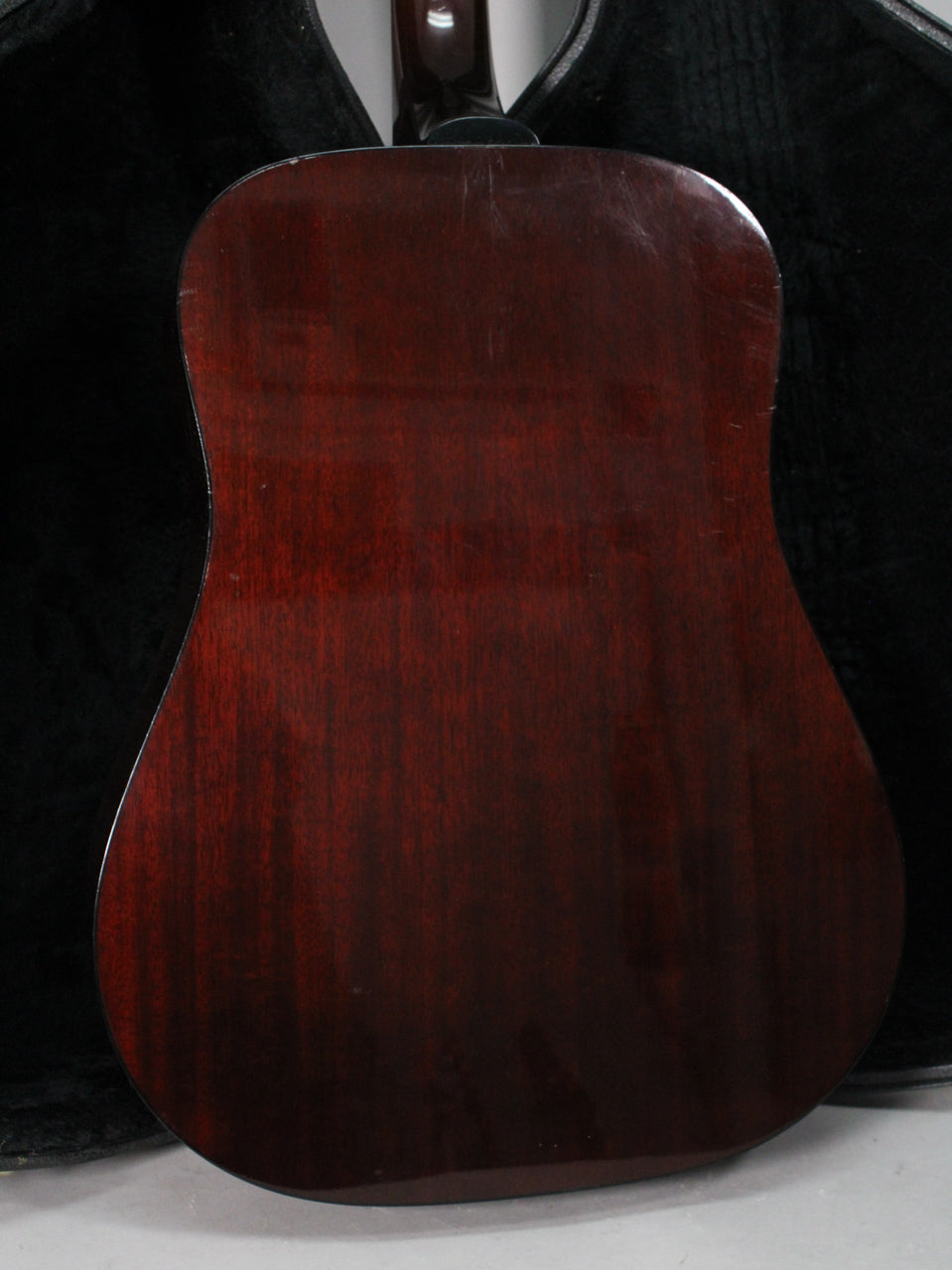 The guitar's dark cherry sunburst back shows light surface scratches and a few small dings, with the neck heel visible.