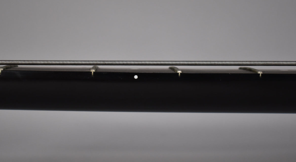 Close-up of the black bass neck, showing the side dots and frets with a single bass string running above.