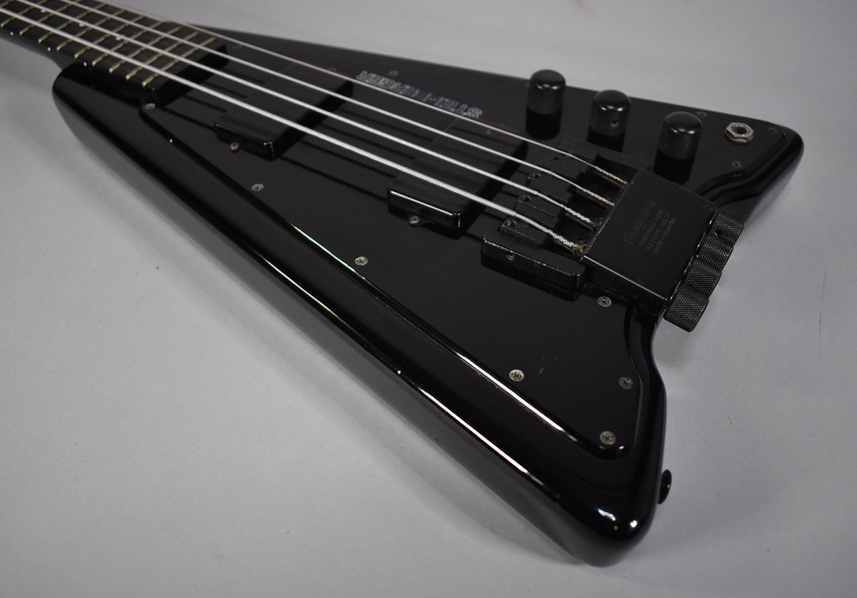 The black Steinberger XP-2 bass body, with two pickups and three control knobs, shows minor wear on its glossy finish.