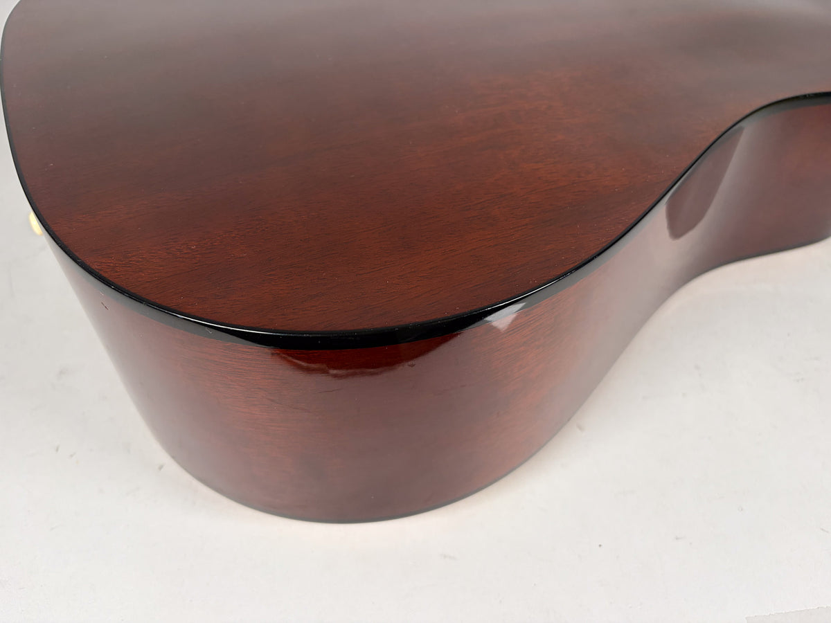 Close-up of the lower bout's dark brown, glossy side and back, showing a small chip on the binding and light surface wear.