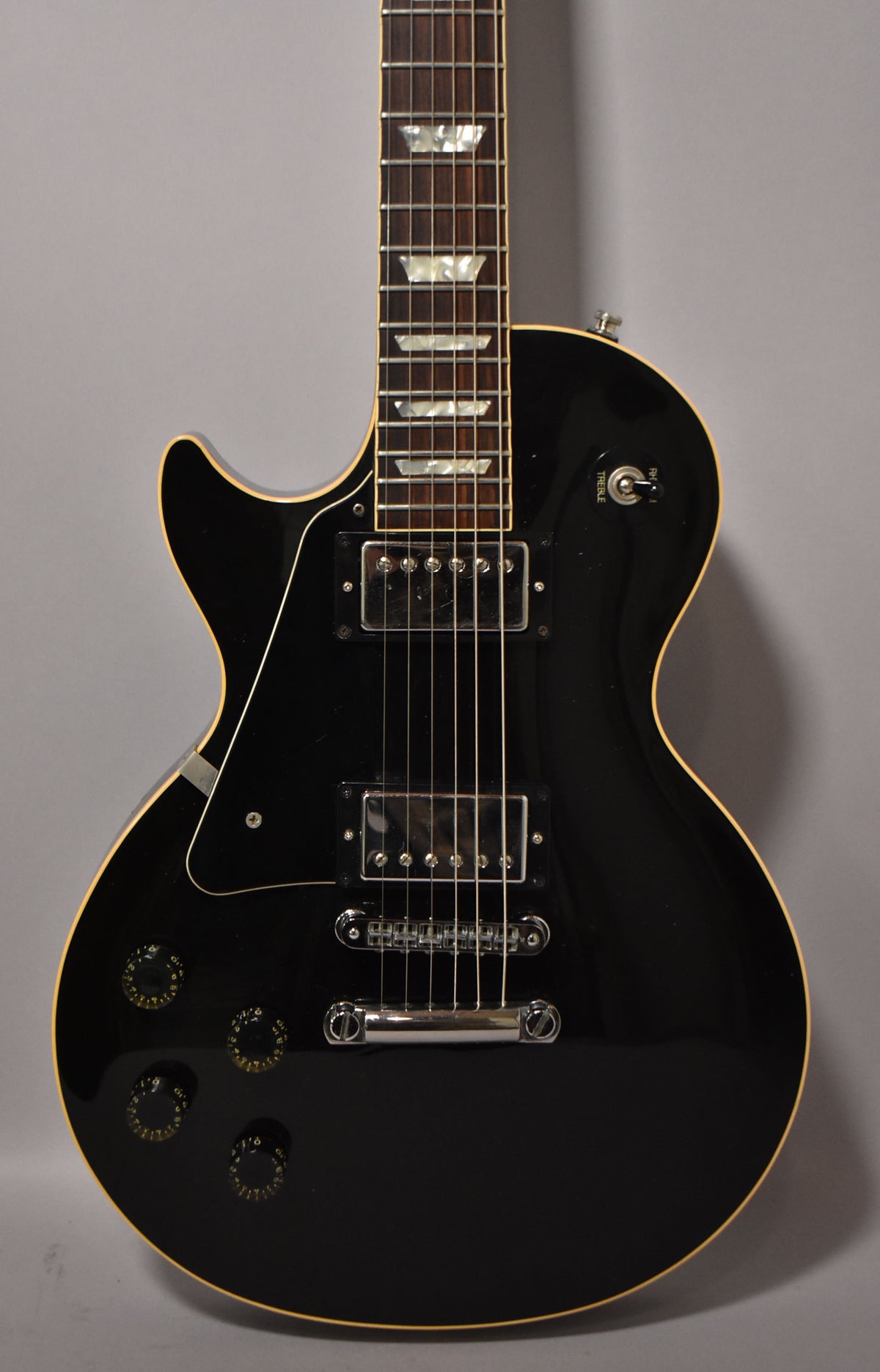 Ebony left-handed electric guitar, angled from the neck down, showing the dark fretboard with trapezoid inlays, two humbuckers, and four control knobs.