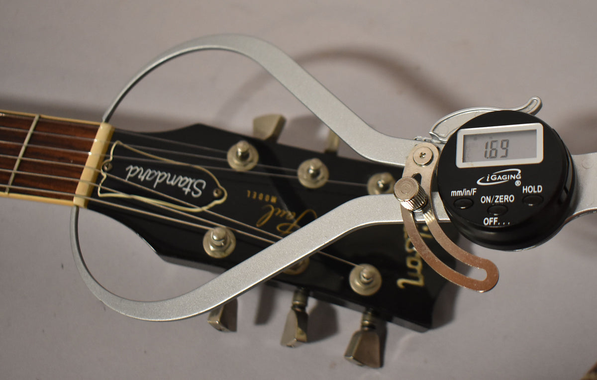 Close-up of the ebony headstock with a digital caliper measuring the nut width at 1.69 inches.