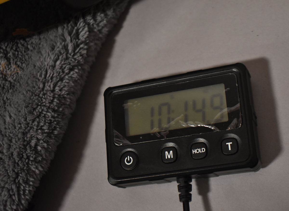 A black digital scale shows a reading of "10.149" on its cracked screen, next to a gray plush surface.