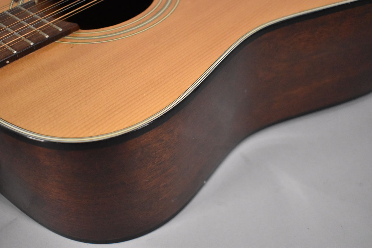 Close-up of the guitar's lower bout, showing the light-colored spruce top with binding and the dark, matte-finished mahogany side.