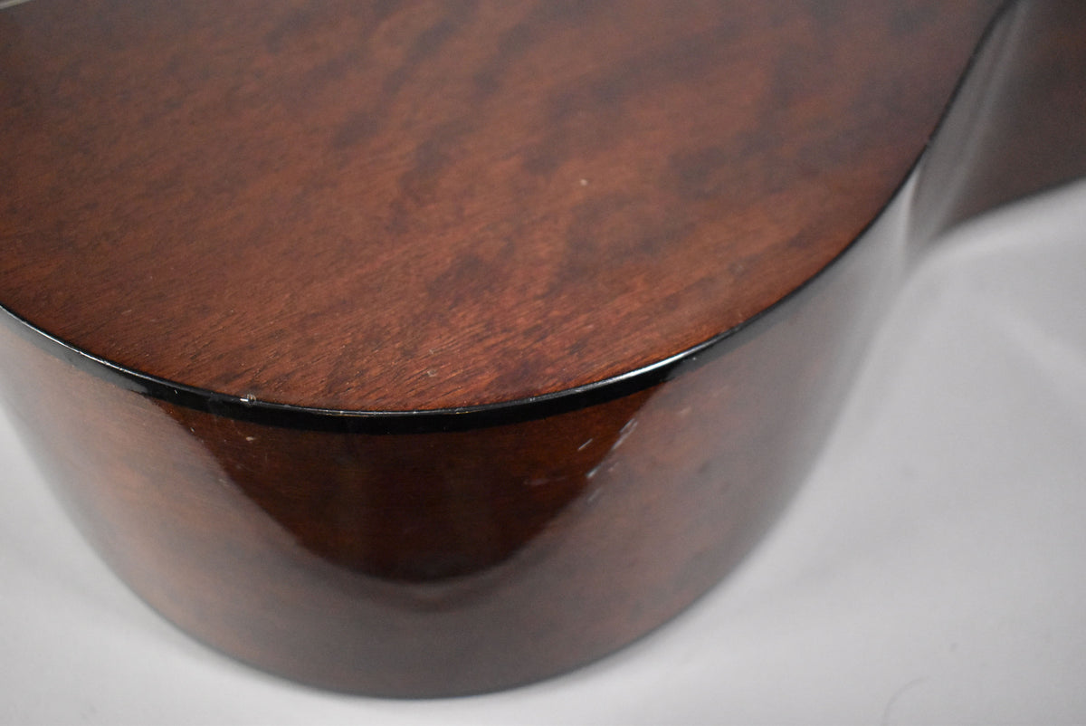 Close-up of the guitar's lower bout, showing the dark brown wood grain top, glossy dark brown sides, and light scuffs on the binding.