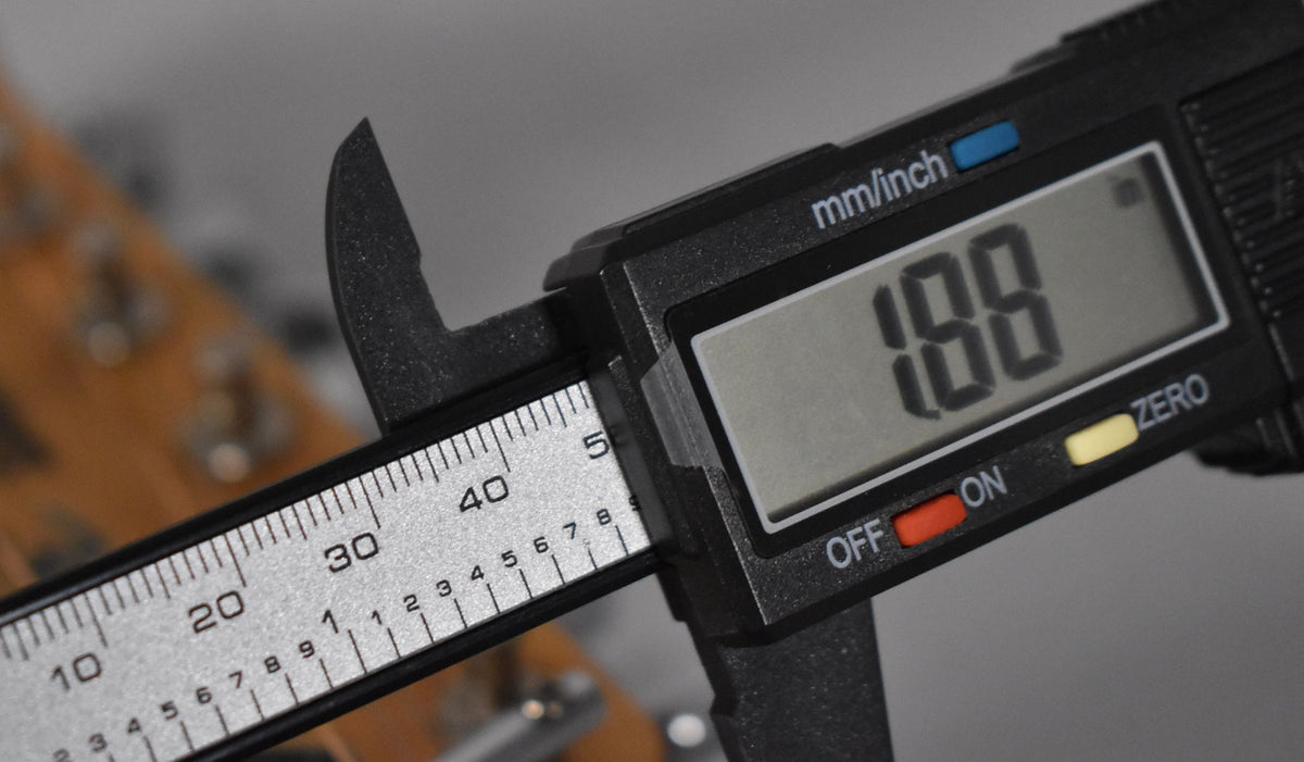 The guitar's natural wood headstock is visible from the side, with a digital caliper measuring the nut width at 1.88 inches.