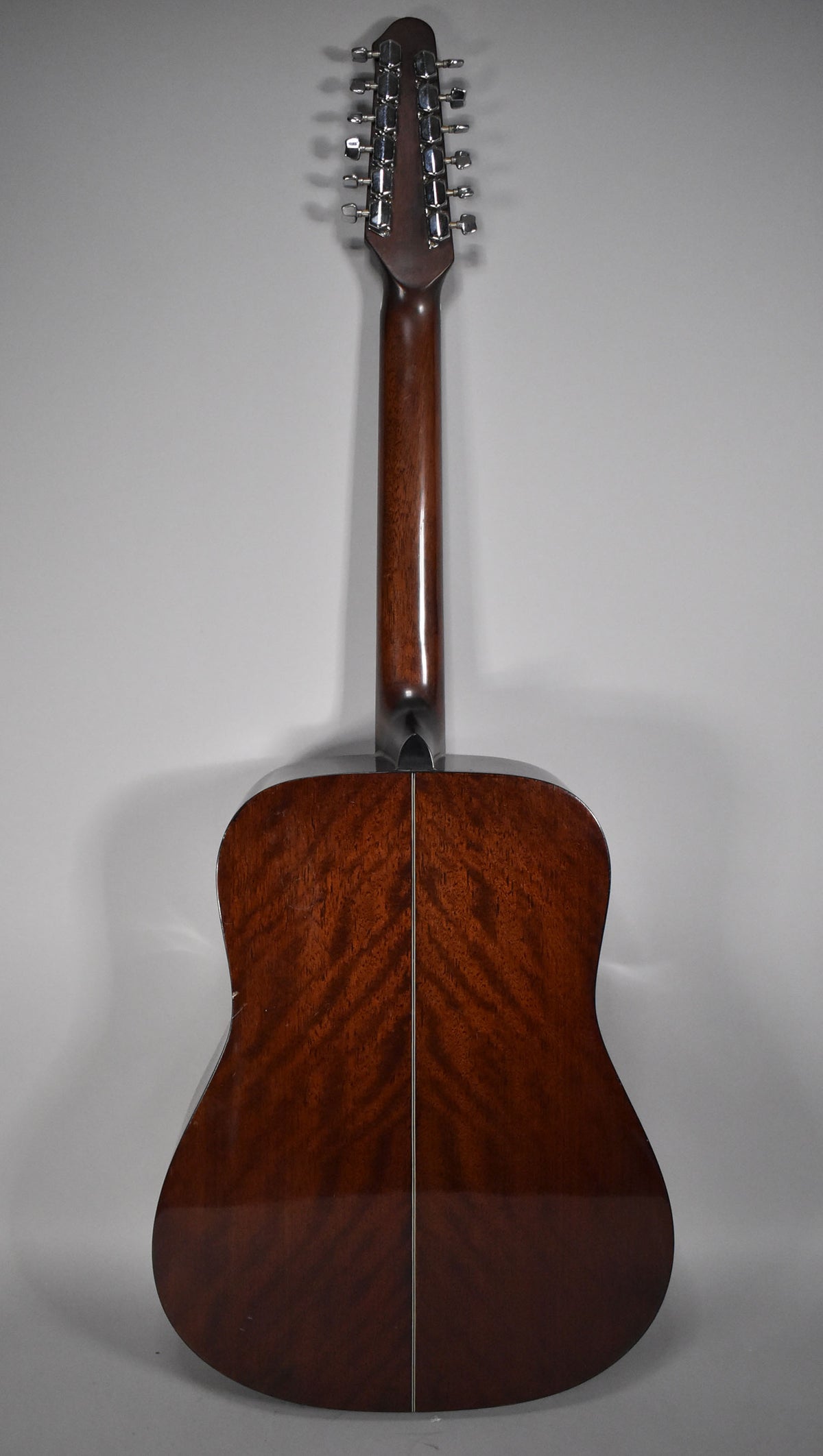The guitar's back and neck are a rich, dark brown with a glossy finish, showing subtle wood grain and a center seam.